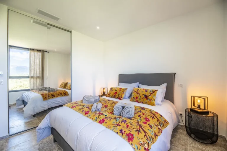 Chambre double avec grand placard miroir et linge de lit fleuri