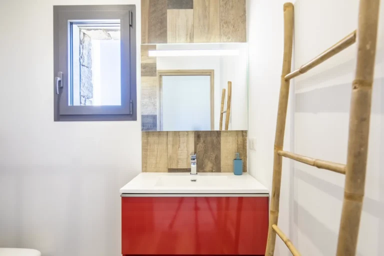 Salle d’eau avec meuble rouge et échelle porte-serviettes