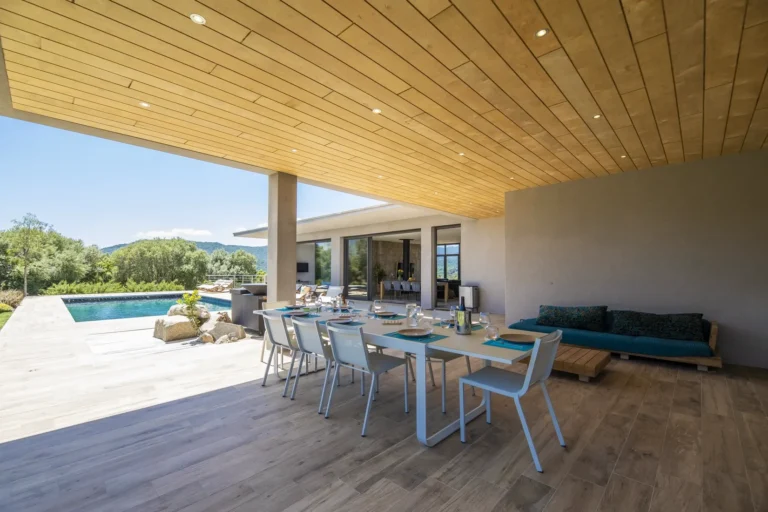 Terrasse couverte avec table et salon face à la piscine