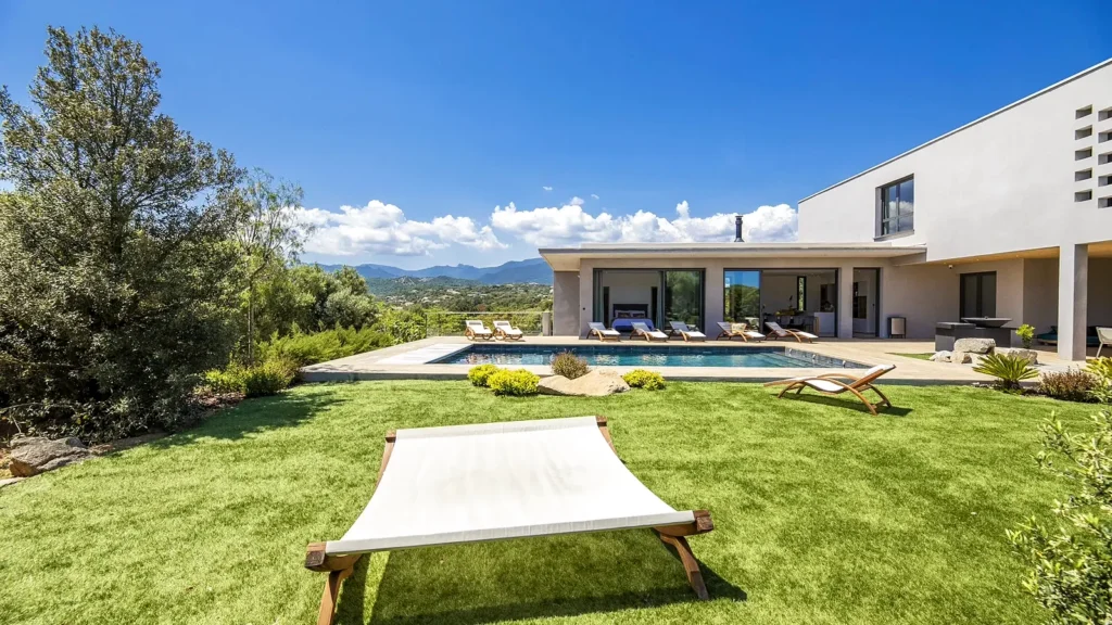 Jardin méditerranéen de la villa avec hamac, piscine et montagnes au loin
