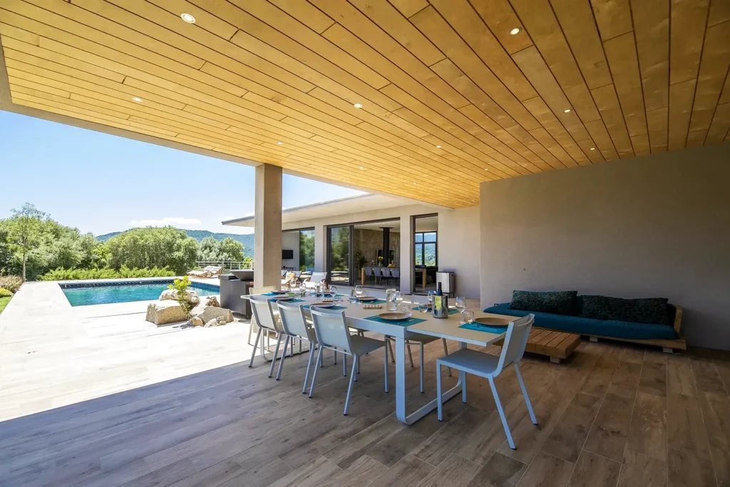 Grande table sous la terrasse couverte, ouverte sur la piscine